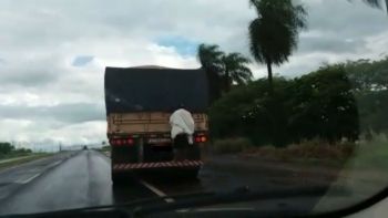 Rapaz viajava agarrado atrás de caminhão em rodovia; veja o vídeo