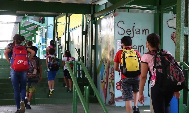 Rio de Janeiro - Crianças do ensino fundamental chegam para as aulas presenciais na Escola Estadual Terezine Arantes Ferraz Bibliotecaria, no Parque Casa de Pedra, zona norte da capital