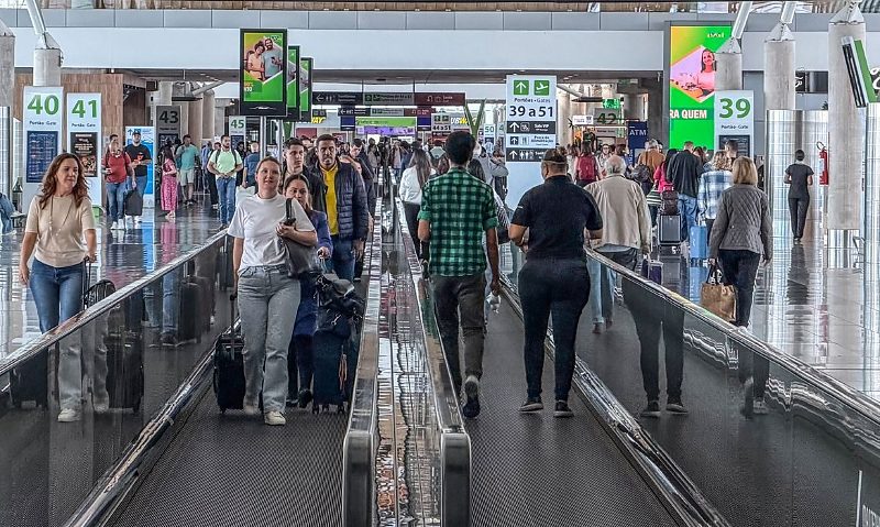 Brasília (DF), 17/03/2026 – Movimentação de passageiros no Aeroporto de Brasília durante operações de embarque e desembarque. Pessoas circulam pelos terminais com bagagens enquanto aviões realizam pousos e decolagens, refletindo o fluxo intenso de vi