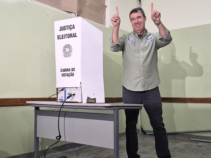 O governador Eduardo Riedel (PP) faz o número 11 com as mãos ao lado da cabine de votação, na Escola Estadual Maestro Frederico Liebermann, no bairro Monte Castelo, em Campo Grande